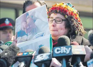  ?? CP PHOTO ?? Jennifer Neville-Lake cries as she shows photograph­s of her three children and father who were killed in a horrific crash by drunk driver Marco Muzzo at the courthouse in Newmarket, Ont., on Tuesday.