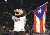  ?? Ricardo Arduengo / Getty Images ?? Minnesota Twins mascot TC Bear carries the Puerto Rican flag at Hiram Bithorn Stadium on Wednesday.