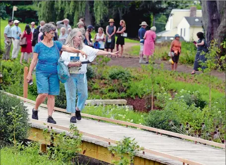  ?? SARAH GORDON/THE DAY ?? Donna Poland, left, and friend Wendy Warburton, visiting from Rhode Island, point out flowers along the Rainwater Garden during the grand opening of the Robert F. Schumann Artists’ Trail on Monday at the Florence Griswold Museum in Old Lyme. The trail connects parcels of the original Griswold property in a half-mile walk that surrounds the museum featuring natural, artistic and historic highlights.