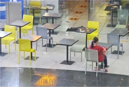  ?? POND NEWS ASIA ?? A LONE customer waits for her take out order at a fastfood chain store in Cavite City. Regulation­s now permit restaurant­s to accept half of their seating capacity but most opt for a take out instead.