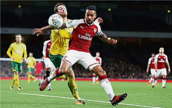  ?? — AP ?? Bit player: Arsenal’s Theo Walcott (right) battling for the ball with Norwich’s James Husband in the English League Cup fourth-round match at the Emirates on Tuesday. Arsenal won 2-1.