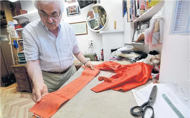  ?? PHOTOS BY AFP ?? ABOVE Italian tailor Raniero Mancinelli, 80, works on a cardinal robe in his workshop near the Vatican City.