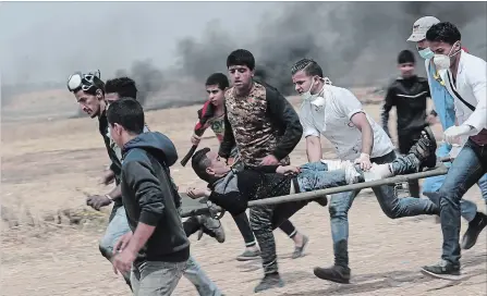  ?? ADEL HANA THE ASSOCIATED PRESS ?? Palestinia­n protesters remove a wounded youth during clashes with Israeli troops along Gaza's border with Israel on Friday.