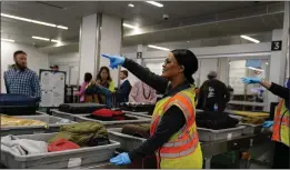  ?? BRYNN ANDERSON — THE ASSOCIATED PRESS ?? A worker points as people wait for their belongings at the Transporta­tion Security Administra­tion security area at the Hartsfield-Jackson Atlanta Internatio­nal Airport on Jan. 25 in Atlanta.