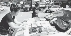  ?? — Gambar Bernama ?? DILANDA BANJIR: Penduduk Taman Thean Teik, Air Itam menjemurka­n buku-buku sekolah yang basah selepas kawasan berkenaan dilanda banjir kilat di George Town, semalam.