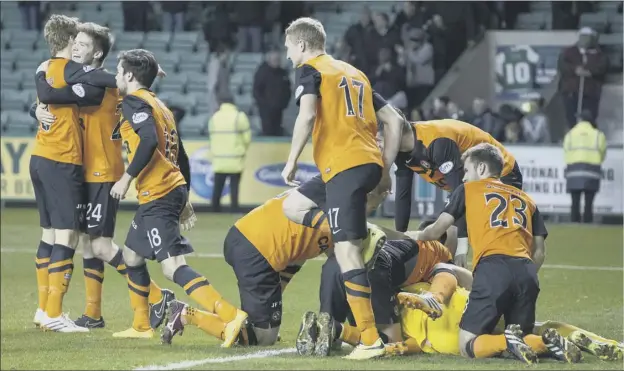  ?? Picture: SNS ?? Delighted Dundee United players engulf goalkeeper Radoslaw Cierzniak after his penalty kick heroics in which he saved from Hibs’ Matthew Kennedy and David Gray