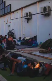  ??  ?? A migrant checks his mobile phone at dusk near a new makeshift camp on the Greek island of Lesbos yesterday.