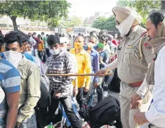  ?? REUTERS ?? Police stop a migrant worker as he queues with others for medical screening before boarding a train in Amritsar yesterday.