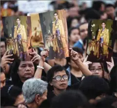  ?? LILLIAN SUWANRUMPH­A/AFP ?? Thai mourners hold aloft pictures of the late King Bhumibol Adulyadej as they gather to commemorat­e his birthday on top of Bhumibol Bridge in Bangkok yesterday.