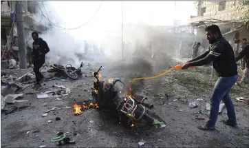  ?? THE ASSOCIATED PRESS ?? A man tries to put out a fire after a car bomb exploded in Tal Abyad, Syria, on Saturday. The blast in the town along the border with Turkey killed over a dozen of people and injured about 20, Turkey’s Defense Ministry said.