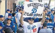  ?? Hayne Palmour IV San Diego Union-Tribune ?? JONATHAN RODRIGUEZ holds up a sign as the Dodgers’ Pantone 294 club gathers at a San Diego bar.