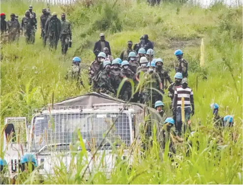  ?? JUSTIN KABUMBA/THE ASSOCIATED PRESS ?? United Nations peacekeepe­rs remove bodies from an area in the east of the Democratic Republic of Congo where a UN convoy was attacked Monday. Luca Attanasio, the Italian ambassador to the DRC, was killed in the ambush.
