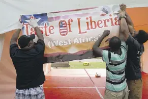  ?? DAVID BLOOM ?? From left, Reuben Tucker, Gizzie Arku and Edmond Wilson set up the Liberian pavilion for the Heritage Festival. More than 1,000 Liberians call Edmonton home and Tucker says they “love to be at a party.”