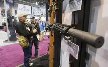  ?? REUTERS ?? People look over Remington rifles and shotguns during the annual SHOT (Shooting, Hunting, Outdoor Trade) Show in Las Vegas on January 15, 2013.