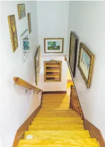  ??  ?? The white walls on either side of the wooden staircase are a showcase space for paintings dear to the couple, produced by artist friends.