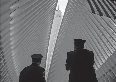  ?? CRAIG RUTTLE/AP PHOTO ?? Two members of the Fire Department of New York look toward One World Trade Center through the open ceiling of the Oculus, part of the World Trade Center transporta­tion hub in New York on Tuesday, the 17th anniversar­y of 9/11 terrorist attacks. The transit hall ceiling window was opened just before 10:28 a.m., marking the moment that the North Tower of the World Trade Center collapsed on Sept. 11, 2001.