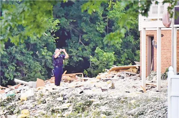  ?? ASSOCIATED PRESS FILE PHOTO ?? A policeman stands in the debris following a fatal house explosion July 2, 2017, in Manor Township, near Millersvil­le, Lancaster County. Federal investigat­ors have blamed the blast, which killed a UGI Utiliities worker, on a faulty natural gas connection.