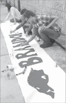  ?? LYNN KUTTER ENTERPRISE-LEADER ?? Cassia Maher, left, Khalan Morel and Shawn O’Connor work on a banner for a scene in the movie, “Greater,” about University of Arkansas standout Brandon Burlsworth. The movie used the Farmington Cardinal gym to film Burlsworth’s memorial service.