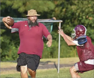  ??  ?? Head coach Chris Norton controls the football during a workout with sophomore Robbie Lee.