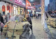  ??  ?? AVOVE An elderly woman pushes a cart filled with discarded cardboard in the Sham Shui Po district in Hong Kong.