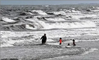  ?? GERRY BROOME / AP ?? People enjoy the ocean at Kure Beach, N.C., on Monday as Tropical Storm Isaias approaches. North Carolina Gov. Roy Cooper warned residents the storm could be dangerous regardless of its strength.