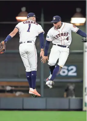  ??  ?? Astros infielders Carlos Correa, left, and George Springer celebrate their playoff win over the Indians on Saturday in Houston.