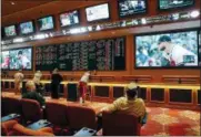  ?? JOHN LOCHER — THE ASSOCIATED PRESS ?? People make bets in the sports book at the South Point hotel and casino in Las Vegas on Monday. Now that the U.S. Supreme Court has cleared the way for states to legalize sports betting, the race is on to see who will referee the multi-billion-dollar...