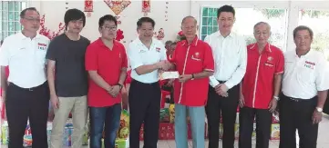  ??  ?? Dr Ting (fourth left) presents the grant to Yee Chiew Seng, a representa­tive of the home, while Ling (third right) and others look on.