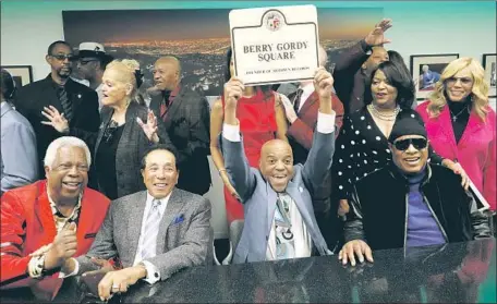  ?? Al Seib Los Angeles Times ?? MOTOWN RECORDS founder Berry Gordy, holding up his sign, is f lanked by Stevie Wonder, right, and Smokey Robinson at Monday’s dedication ceremony in Hollywood. Gordy started the Detroit label in 1959 and moved it to Sunset Boulevard and Argyle Avenue in 1972.