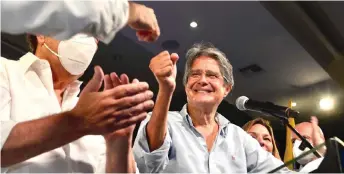  ?? AFP photo ?? Lasso (centre) gestures next to his wife Maria de Lourdes Alcivera (right) and Former Guayaquil Mayor Jaime Nebot as he celebrates his victory after knowing the preliminar­y results of the election runoff at the Convention­s Center in Guayaquil, Ecuador. —