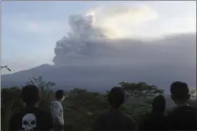  ?? FIRDIA LISNAWATI — THE ASSOCIATED PRESS ?? Villagers watch the Mount Agung volcano erupting during sunrise in Karangasem, Bali island, Indonesia, Sunday. A volcano on the Indonesian tourist island of Bali erupted for the second time in a week on Saturday, disrupting internatio­nal flights even...