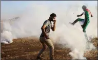  ?? AP/ADEL HANA ?? Palestinia­n protesters endure blasts of tear gas fired Friday by Israeli troops during clashes at the Gaza Strip border fence.