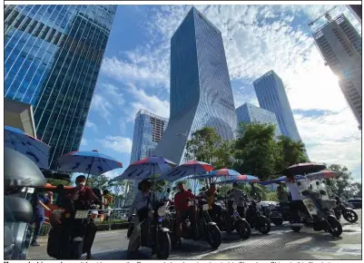  ?? (AP) ?? Men on electric scooters wait for riders near the Evergrande headquarte­rs (center) in Shenzhen, China, in this file photo.