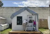  ?? LISA KOGAN — AMIKAS ?? Community volunteers install a steel door on cabin six at Meridian Baptist Church in El Cajon.