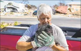  ?? Mark Wallheiser For The Times ?? REBECCA ADKISSON, with her dog Bella, lost her home in Mexico Beach. The town was never a brash tourist strip or fancy playground for the rich.