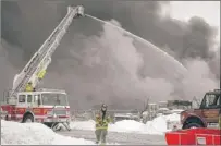  ?? | AP PHOTO ?? A fire fighter walks toward the command center at the scene of a large industrial fire on Sunday at 25790 Woodlawn Ave. in Elkhart.