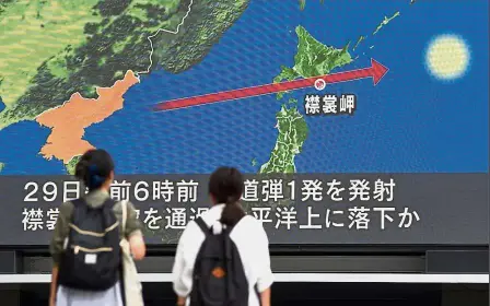  ?? — AFP ?? Worrying sight: Pedestrian­s watching the news on a huge screen displaying a map of Japan and the Korean Peninsula in Tokyo, following a North Korean missile test that passed over Japan.