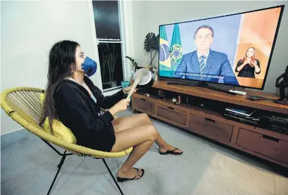  ?? EFE ?? Cacerola en mano y barbijo en boca, una mujer escucha el discurso de Bolsonaro.