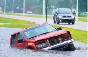  ?? STEVE HELBER/ASSOCIATED PRESS ?? An abandoned vehicle is partly submerged in a ditch next to a near flooded highway as the outer bands of Hurricane Ida arrive Sunday in Bay St. Louis, Miss.