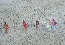  ?? PTI PHOTO ?? People walk along the muddy banks of River Ganga in Allahabad on Tuesday.