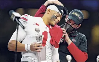  ?? Gerald Herbert / Associated Press ?? Ohio State coach Ryan Day, right, hugs QB Justin Fields after their win against Clemson. Fields said he was aching on every pass after a big hit in the second quarter.