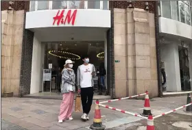  ?? (AP/Chen Cici) ?? Shoppers stand outside an H&M clothing store Friday in Shanghai.