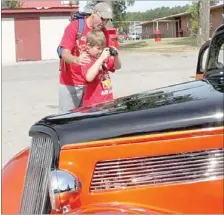  ?? LYNN KUTTER ENTERPRISE-LEADER ?? Travis Boudrey helps his son, Jackson, 8, take a picture of a 1934 Ford, three-window coupe, owned by Tim Clark of Fayettevil­le. More than 70 vehicles registered for the 10th annual Cardinal Car Classic in Farmington.