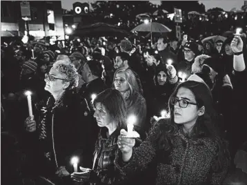  ?? MATT ROURKE/AP ?? People hold candles as they gather for a vigil in the aftermath of a deadly shooting at the Tree of Life Congregati­on.