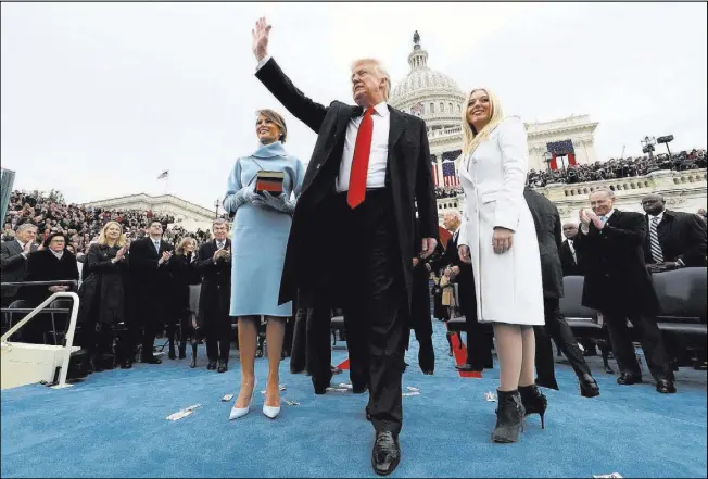  ?? Jim Bourg Reuters ?? President Donald Trump acknowledg­es the audience after taking the oath of office as his wife, Melania, left, and daughter Tiffany watch Jan. 20 during inaugurati­on ceremonies swearing in Trump as the 45th president of the United States on the West...