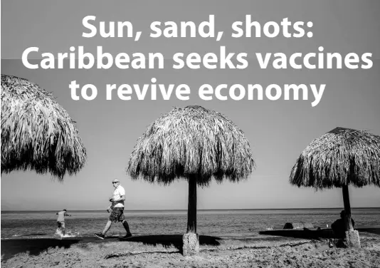  ?? AP ?? A tourist, wearing a protective face mask amid the new cornavirus pandemic, walks along the beach shore in Havana, Cuba, on Tuesday. The Caribbean is hunting for visitors and vaccines to jump-start the stalled economy in one of the world’s most tourism-dependent regions.