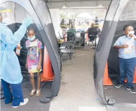  ?? MARTA LAVANDIER/AP ?? Wenderson Cerisene, 7, right, and his sister Dorah, 9, wait Tuesday to get tested for COVID-19 in North Miami, Florida.