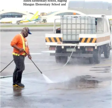  ?? PHOTOGRAPH BY AL PADILLA FOR THE DAILY TRIBUNE @tribunephl_al ?? Clean as they go The tarmac of the Ninoy Aquino Internatio­nal Airport Terminal 2 is hosed down following the delivery of Covid-19 vaccines.