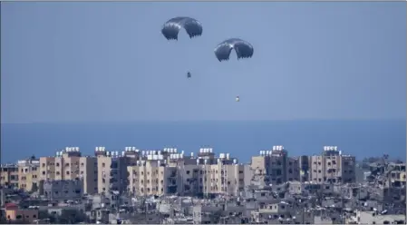  ?? ARIEL SCHALIT — THE ASSOCIATED PRESS ?? Parachutes airdrop humanitari­an aid over the northern Gaza Strip as seen from southern Israel on Tuesday. Fighting has driven a third of the population to the brink of famine.