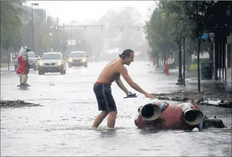  ?? Chris Seward Associated Press ?? TEDDIE DAVIS checks on one of the signature bear statues in downtown New Bern, N.C. It was toppled by the storm on Friday.